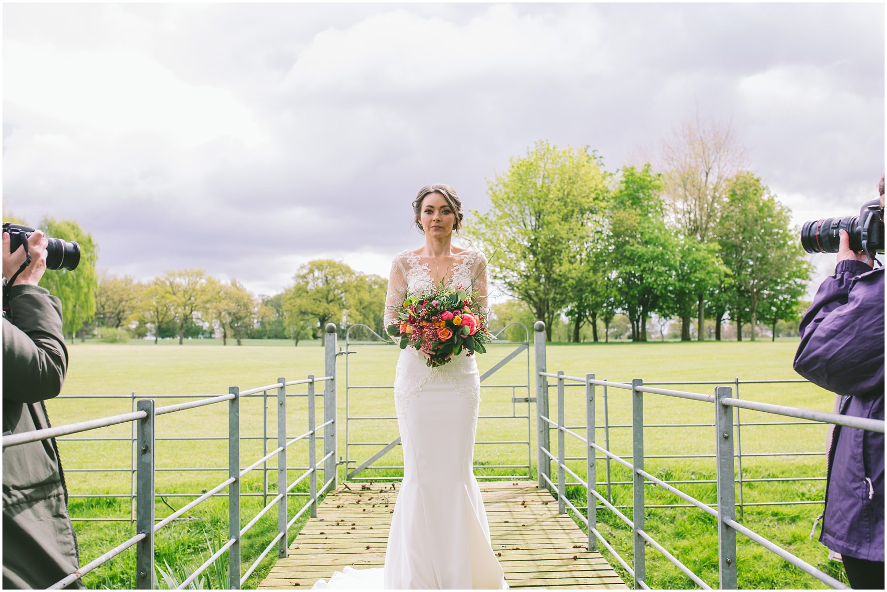 The bride holds her flowers as two photographers create images
