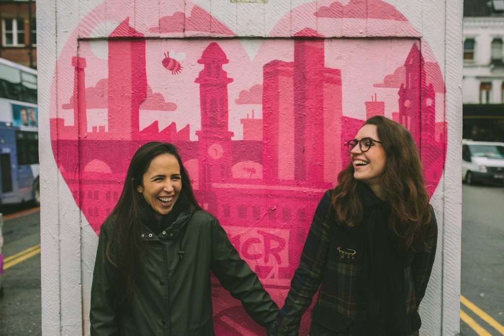two girls stand in front of a graffiti heart in Manchester