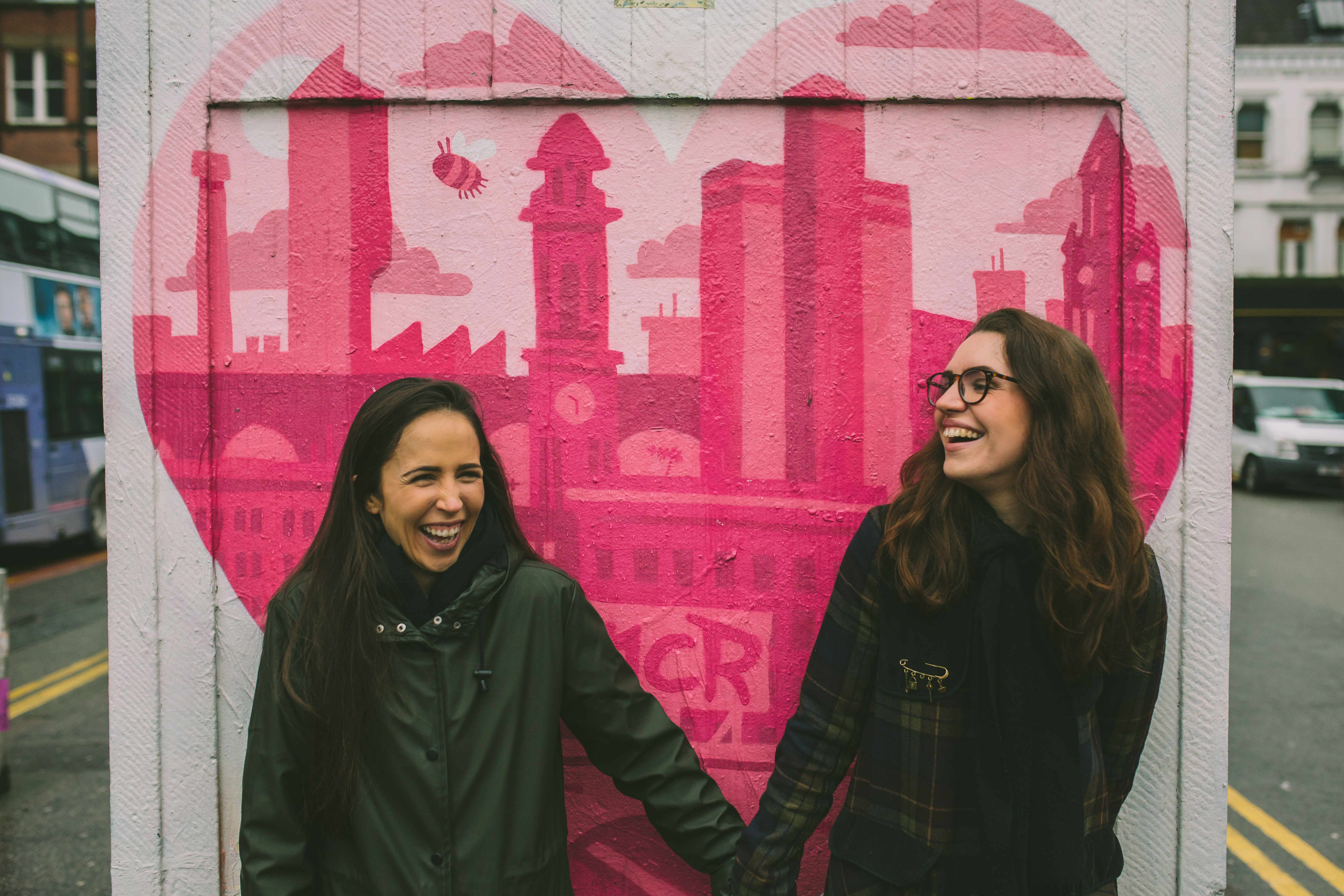 two girls stand in front of a graffiti heart in Manchester