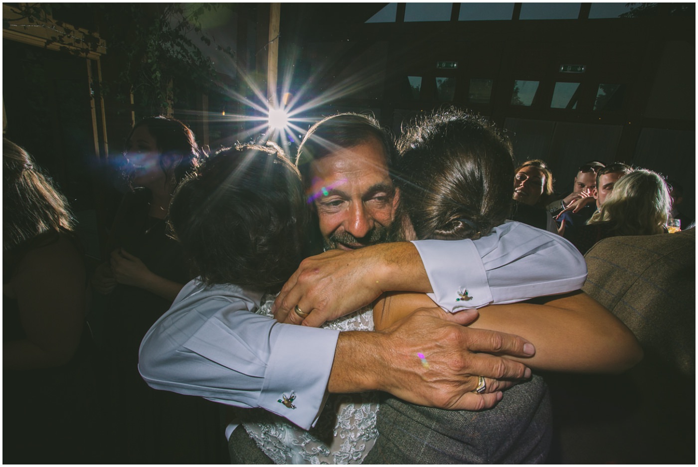 grooms father hugs bride and groom on the dancefloor