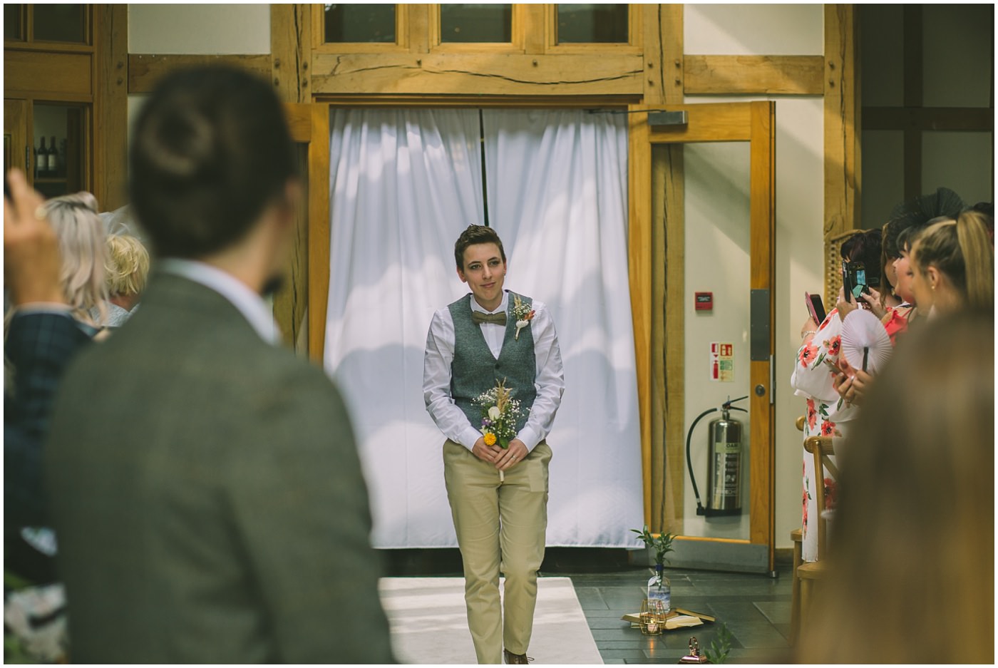 Bridesmaid wearing waistcoat walks down the isle