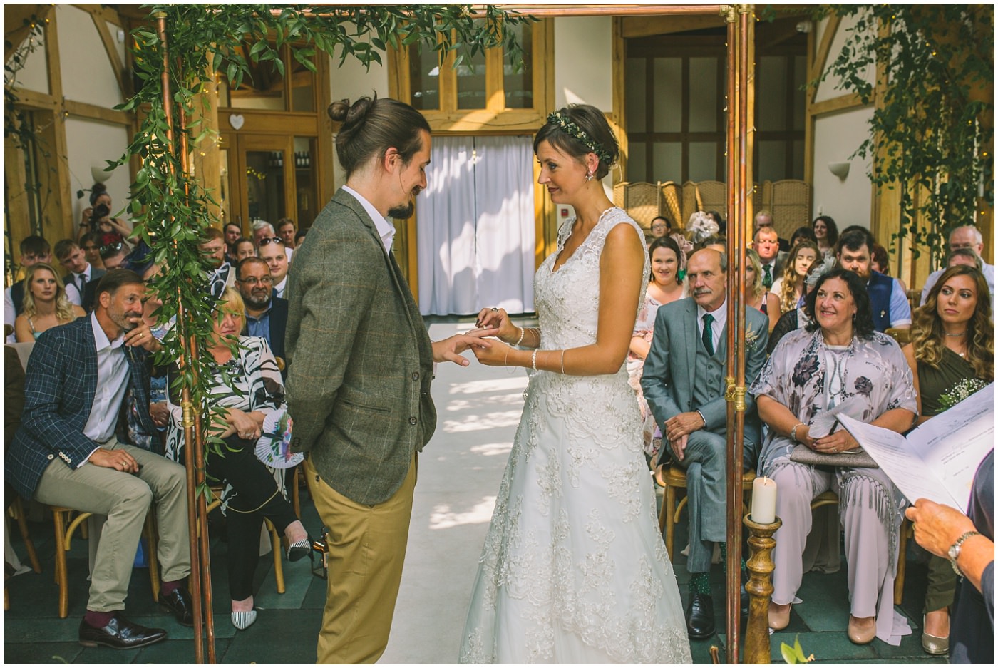 bride gives groom wedding ring in ceremony room at the oak tree of peover