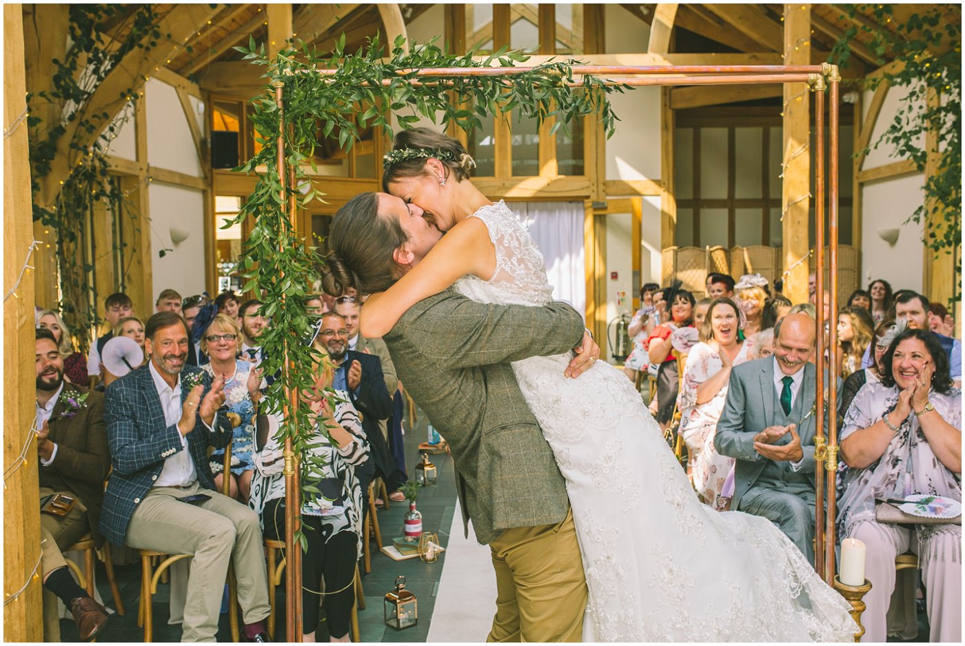 Groom lifts bride as they kiss and a pronounced man and wife