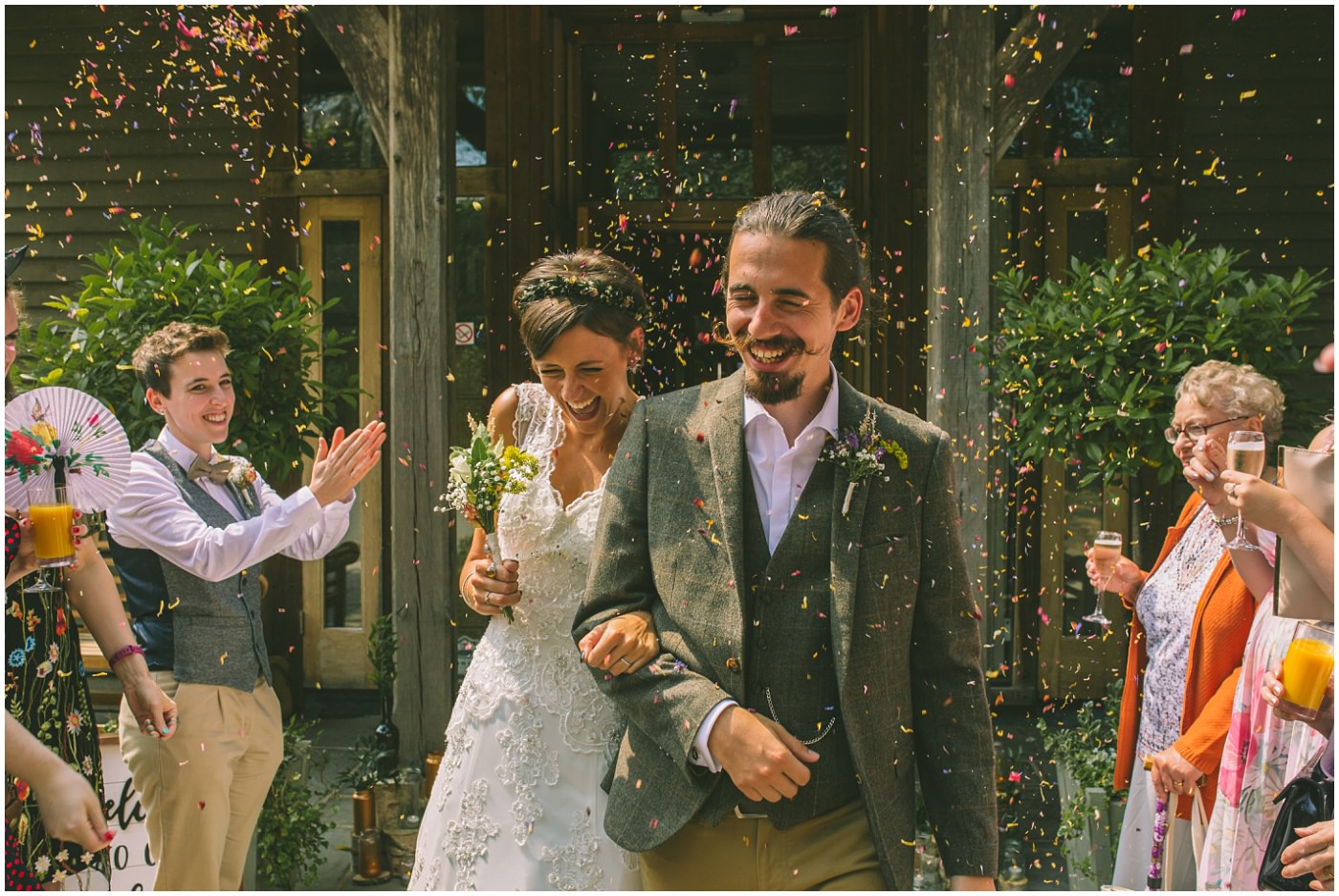 Bride and Groom laugh and smile as they walk through confetti