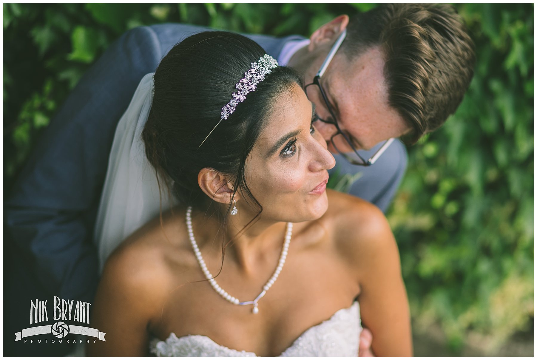 Groom kisses brides cheek during couples portraits