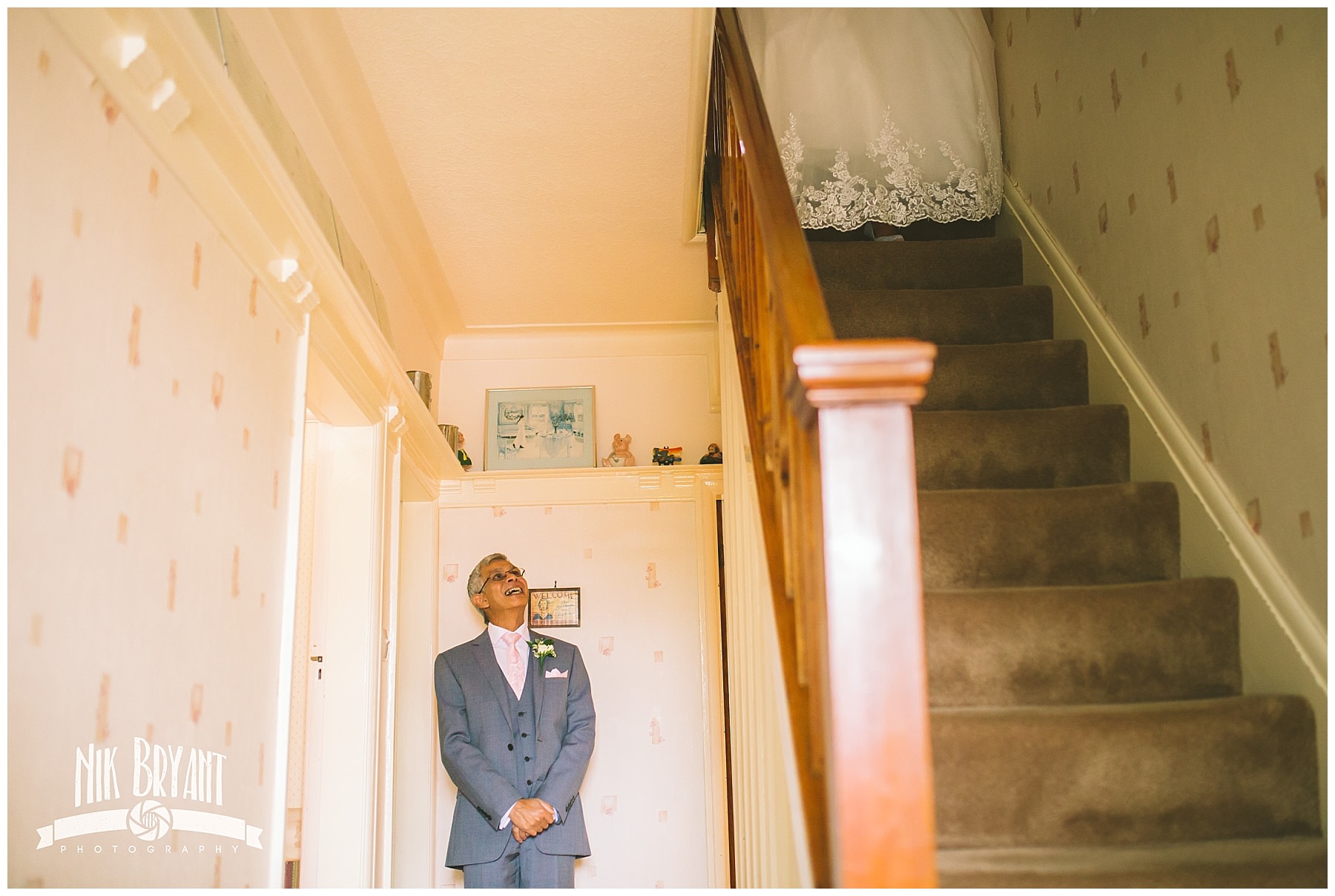 Father of the bride awaits his daughter at the bottom of the stairs