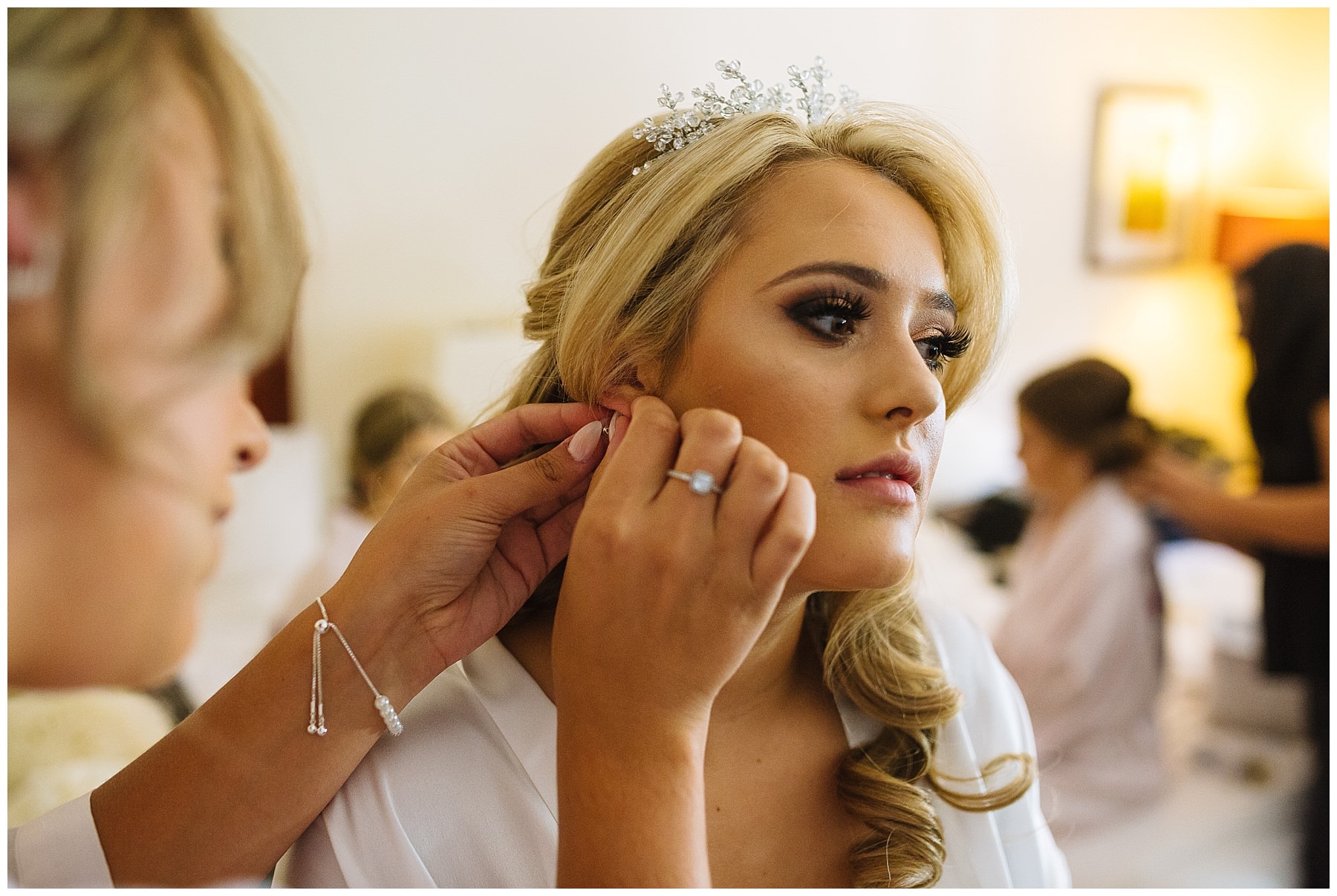 bride has earings put in by bridesmaid