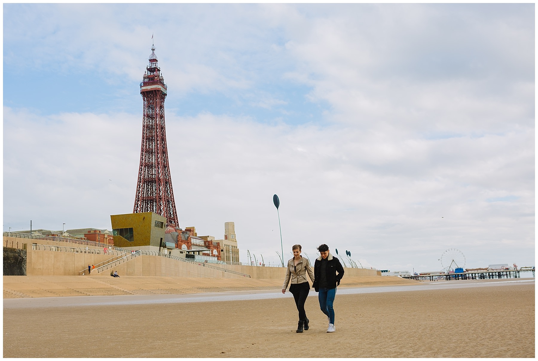 Same sex couple walk along blackpool beach