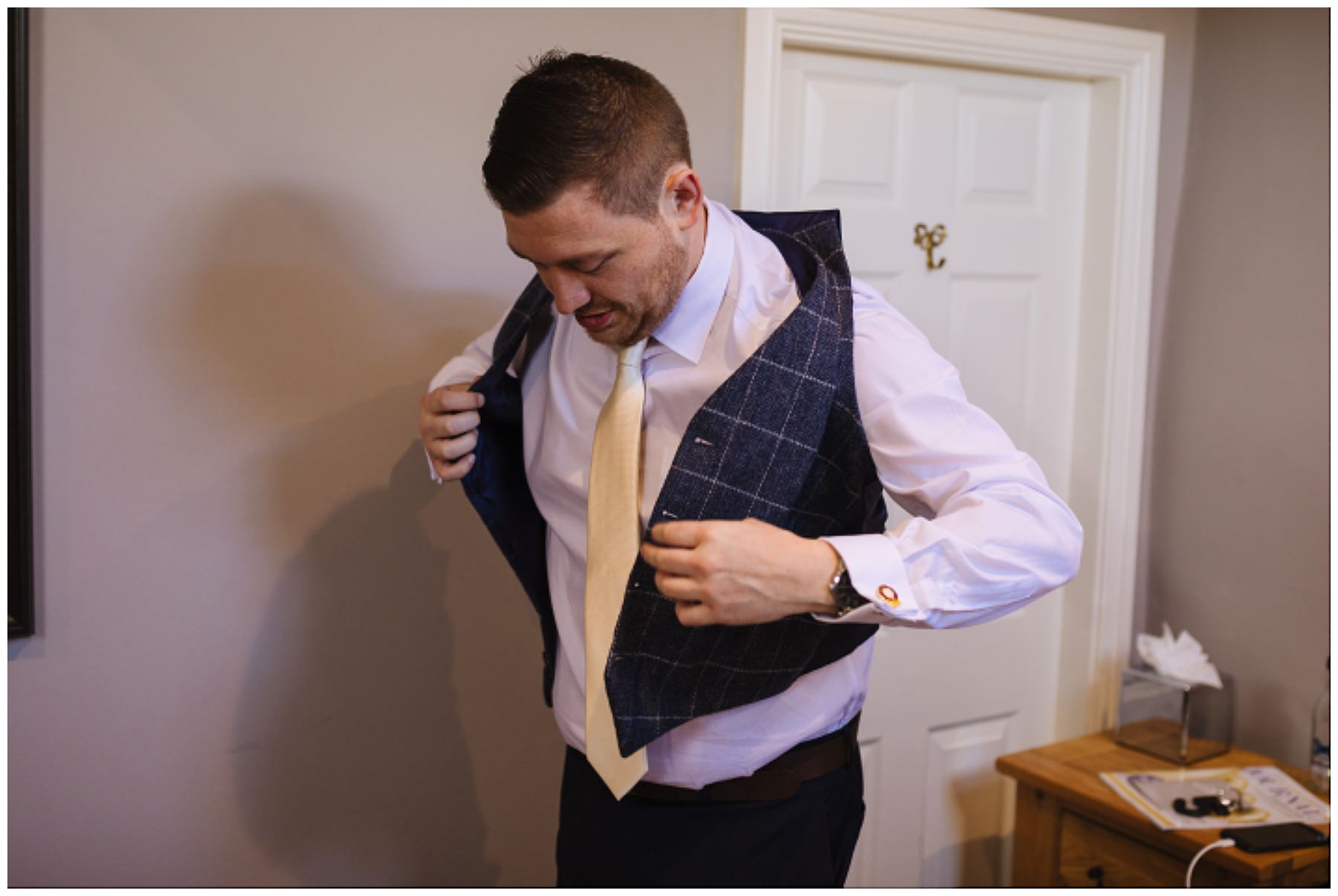 groom puts on waistcoat for eaves hall