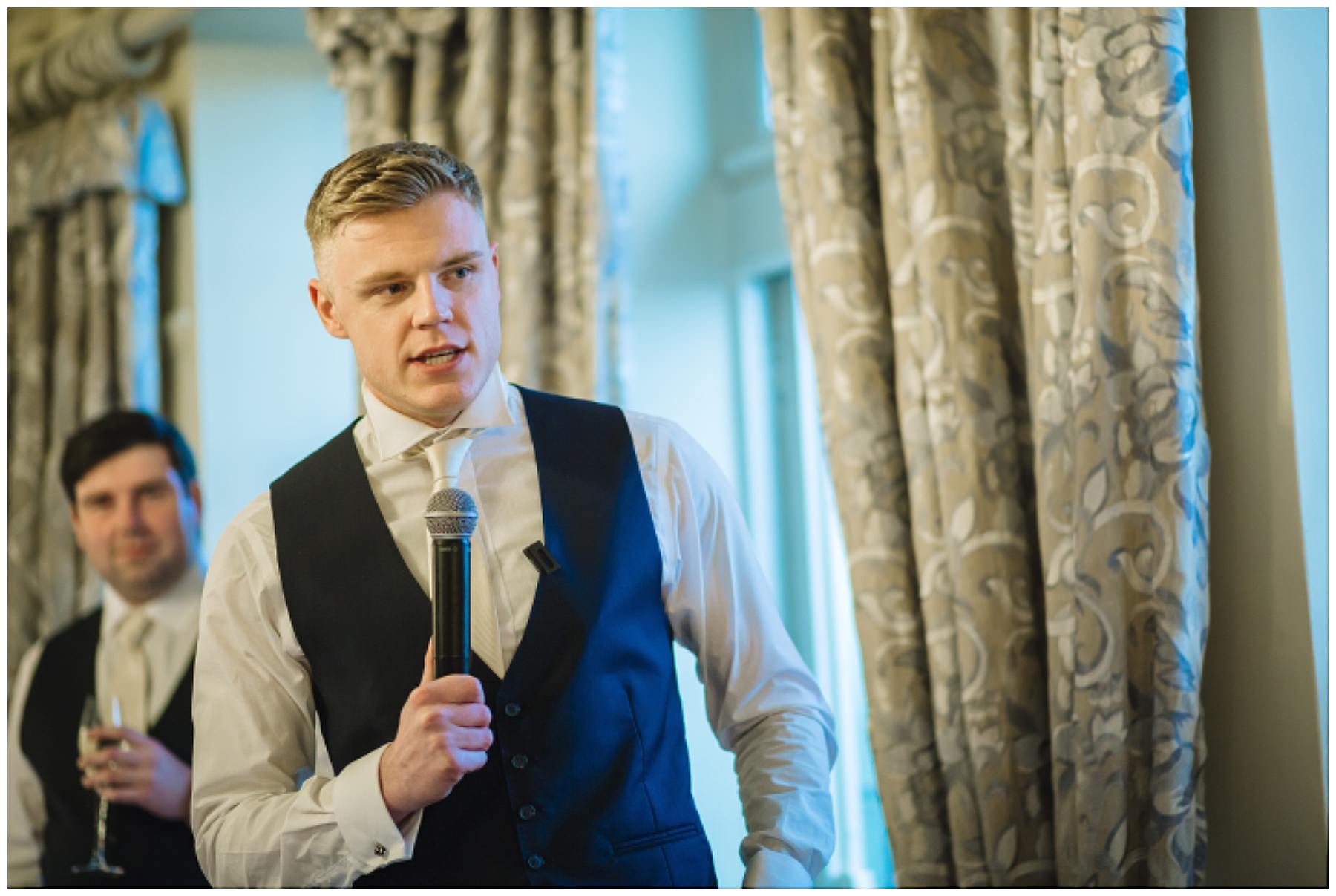 best man looks on to groom during speech