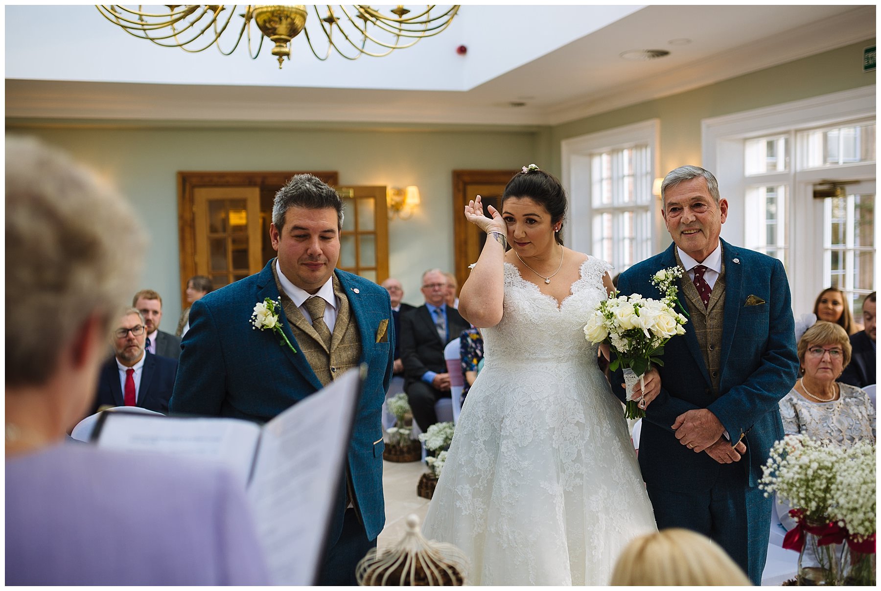 bride wipes a tear from her eye during wedding ceremony
