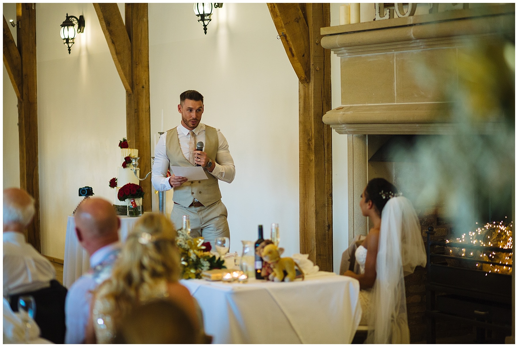 groom stands and speaks to wife during wedding breakfast at swancar farm