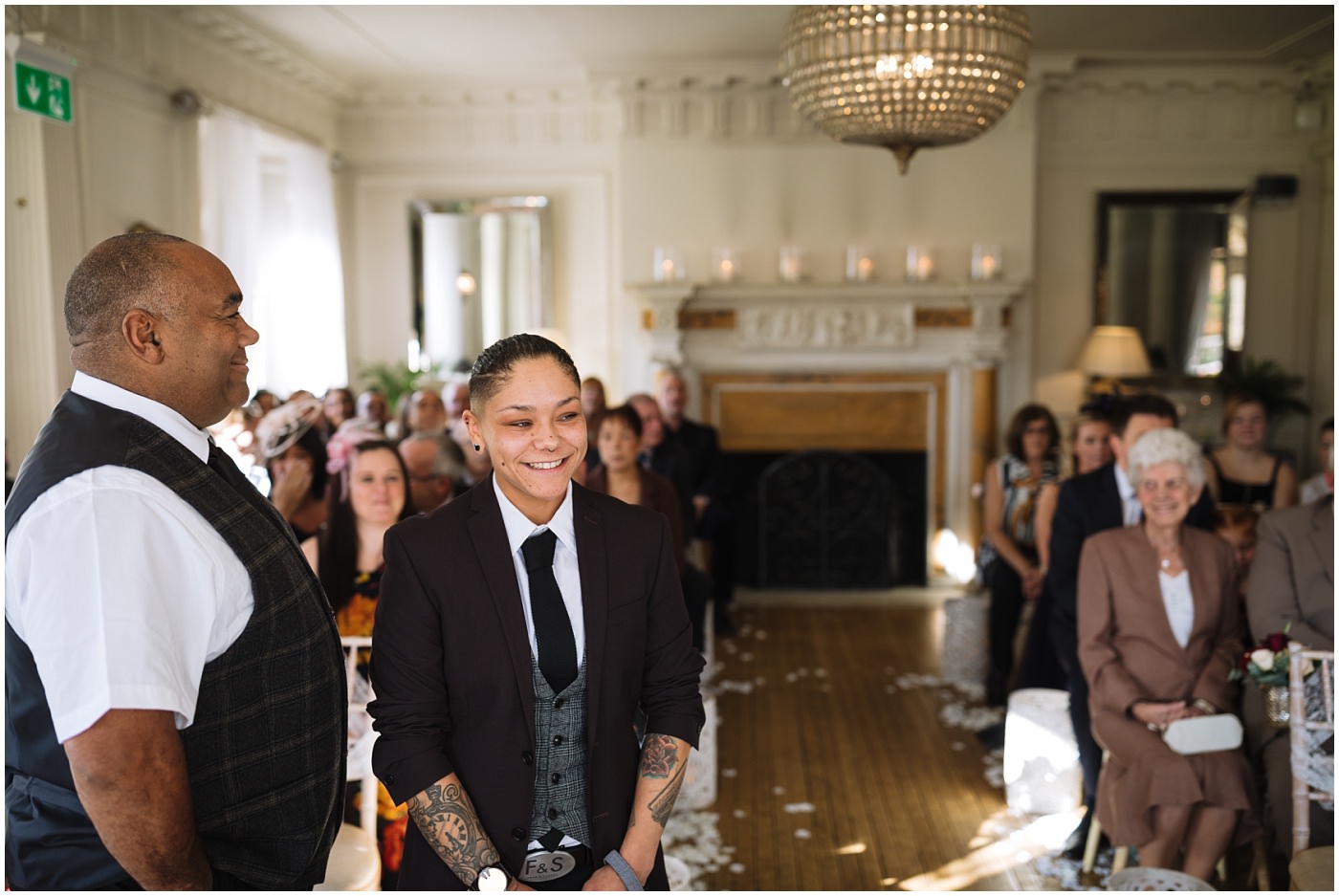 Bride smiles as she awaits her bride to be in the Ballroom at Eaves Hall