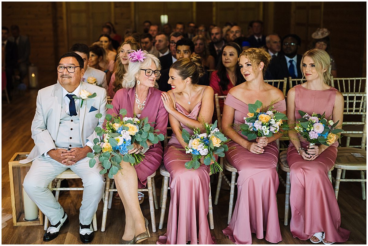 Bridesmaid and mum exchange cheeky giggle during wedding ceremony