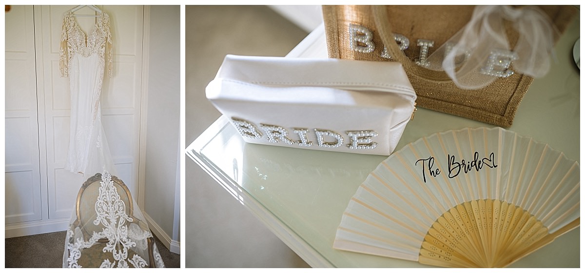 A beautiful bridal gown hanging alongside accessories including a pearl-accented clutch labeled "BRIDE" and a decorative fan labeled "The Bride" on a stylish table.