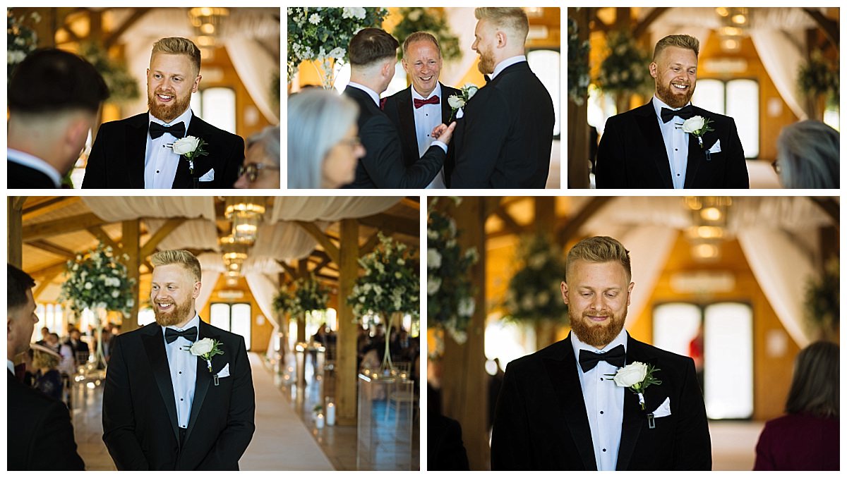 A groom in a black tuxedo smiles while engaging with guests in a beautifully decorated wedding venue.