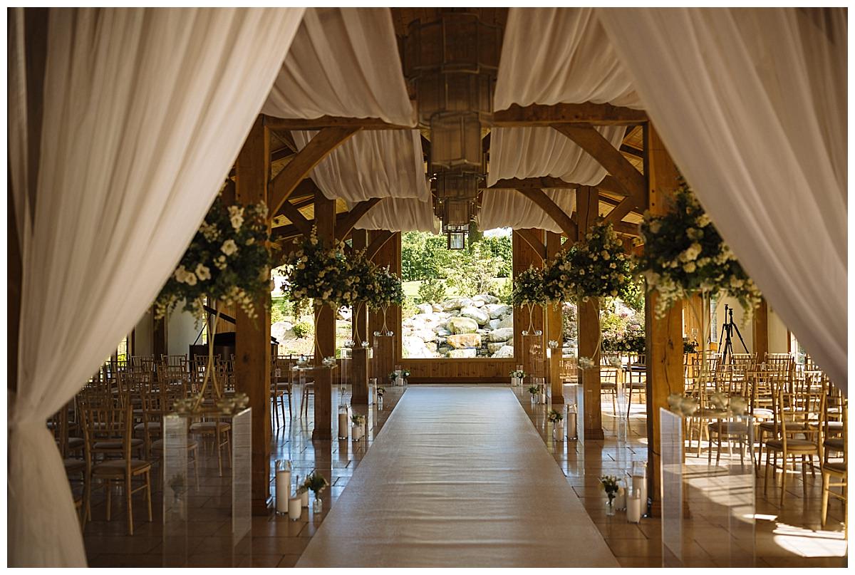 A beautifully arranged indoor wedding ceremony space at Colshaw Hall featuring draped fabric, floral decorations, and a scenic view.