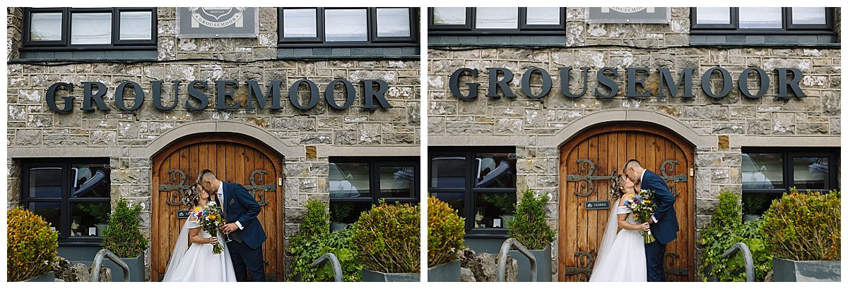 A couple shares a romantic kiss in front of the Grousemoor building, adorned with greenery, as they celebrate their special day.