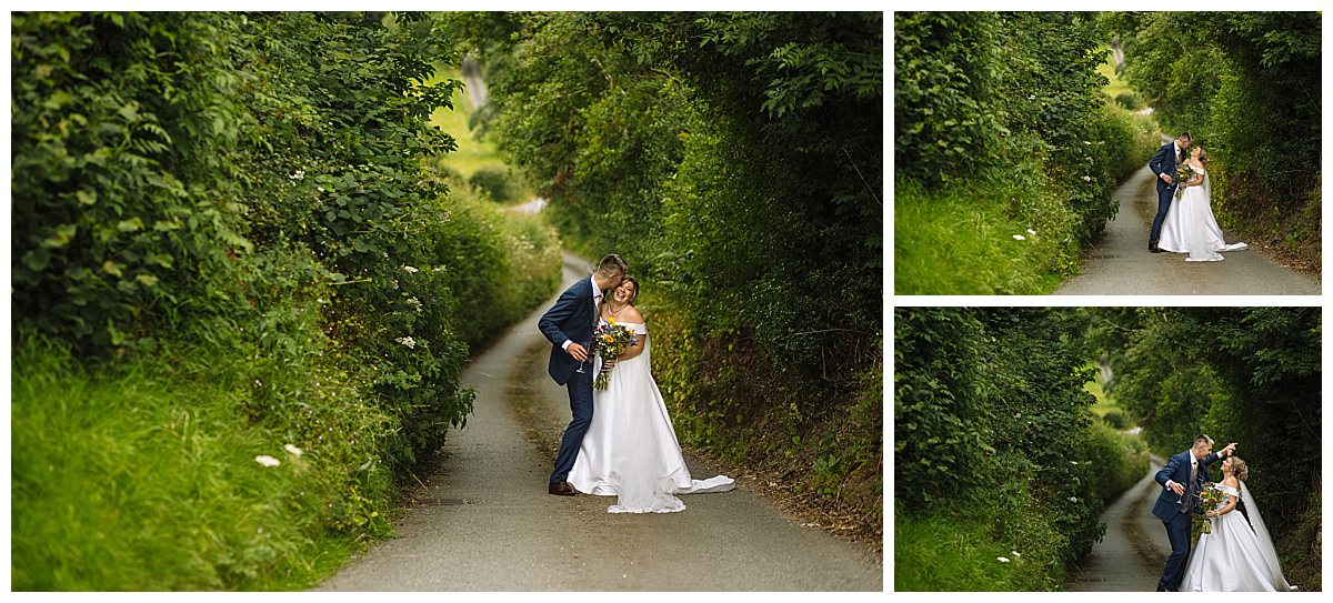 A joyful couple embraces on a scenic, overgrown path, surrounded by lush greenery, celebrating their love on a beautiful day.