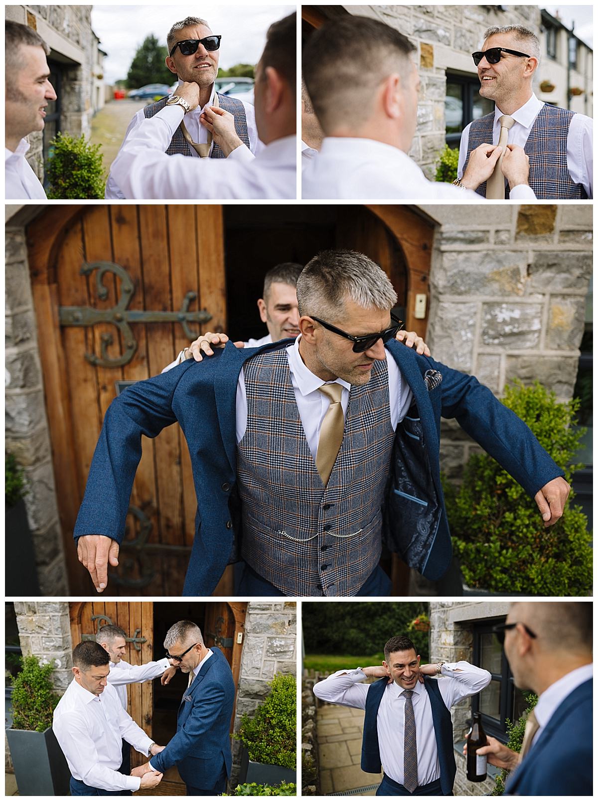 A group of men assisting the groom in putting on his suit jacket while preparing for a wedding outside a rustic building.