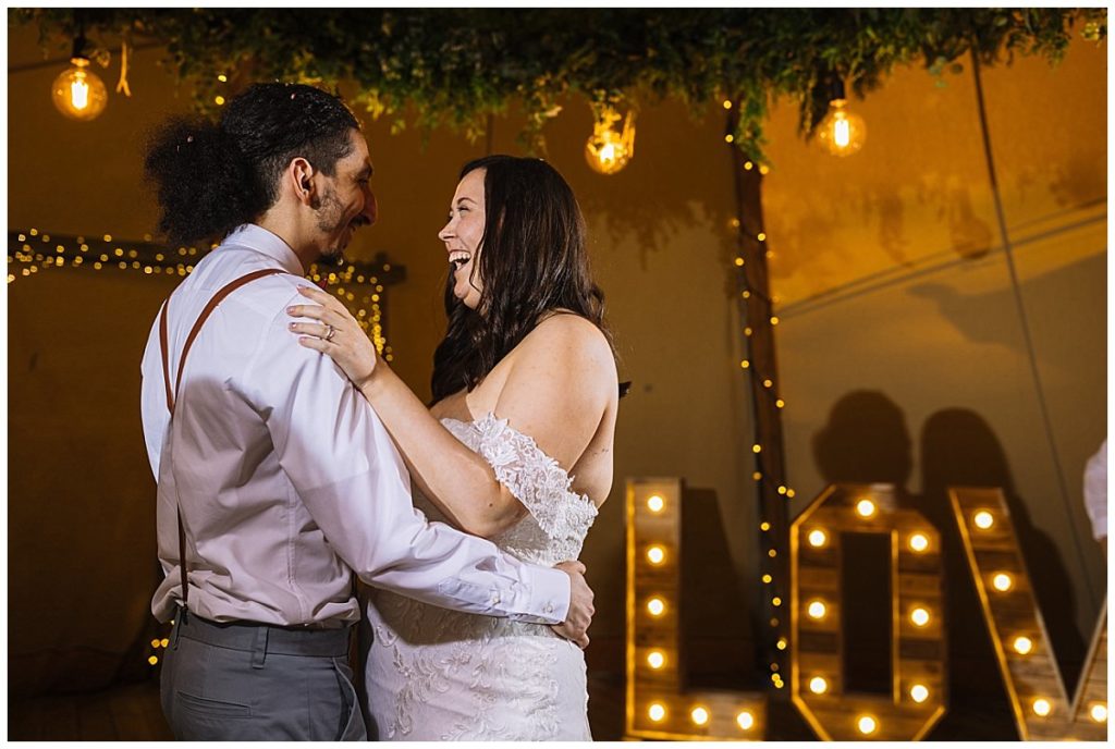 A joyful couple shares a heartfelt moment during their wedding dance, surrounded by romantic lighting and warm ambiance.