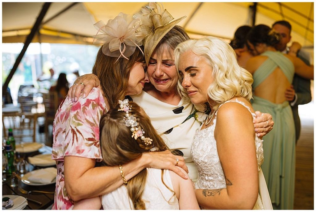 A touching moment of four women sharing an emotional embrace, highlighting love and connection during a special event.