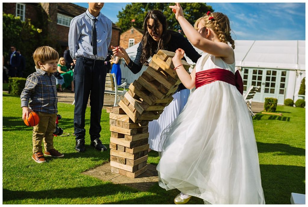 Children and adults enjoying a game of giant Jenga at a beautiful weekday wedding.