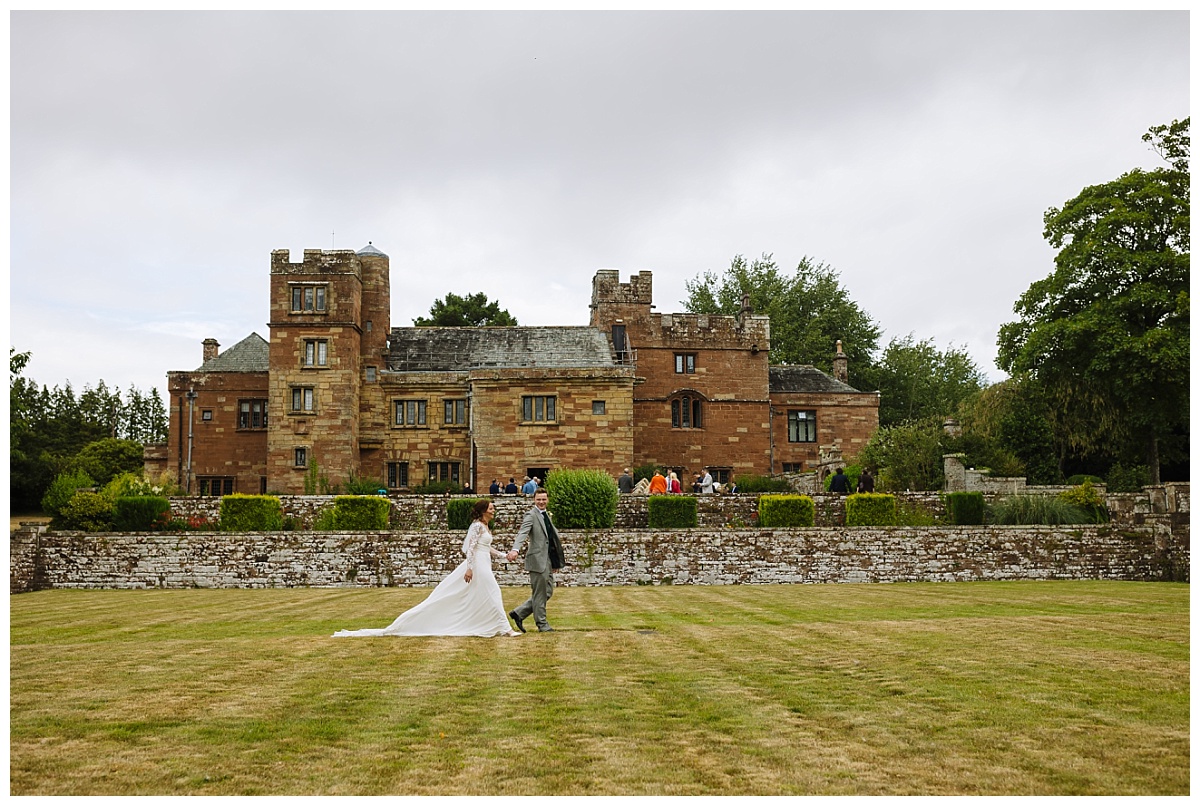 Dalston Hall Wedding Bride and groom walking back towards Dalston Hall in the evening light